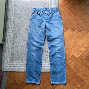 May include: A pair of light blue denim jeans with a button fly and five pockets.