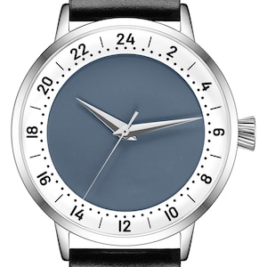 May include: A silver wristwatch with a black leather strap. The watch face has a white background with black numbers and a blue dial. The numbers on the watch face are 12, 1, 2, 3, 4, 5, 6, 7, 8, 9, 10, 11, 12, 14, 16, 18, 20, 22, 24.