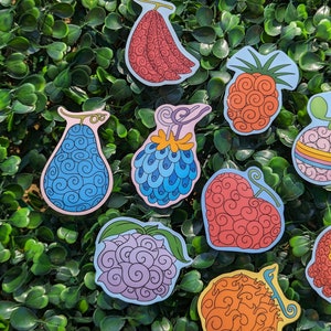 Puede incluir: Un conjunto de diez pegatinas de frutas de colores con un patr&oacute;n de espiral. Las pegatinas est&aacute;n sobre un fondo verde.
