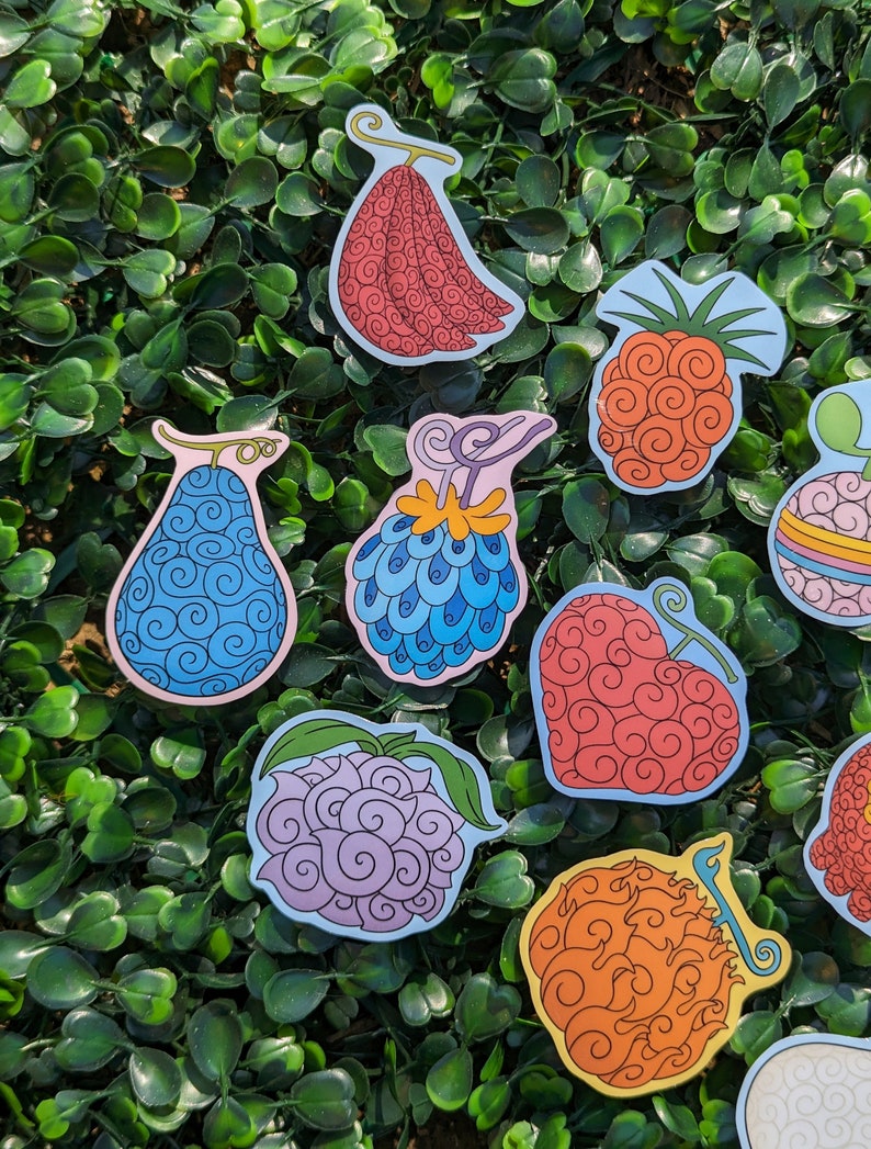 Puede incluir: Un conjunto de diez pegatinas de frutas de colores con un patr&oacute;n de espiral. Las pegatinas est&aacute;n sobre un fondo verde.