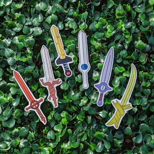 May include: Seven colorful sword stickers with various designs, including a yellow sword with a red handle, a red sword with a white handle, a blue sword with a white handle, a purple sword with a white handle, a green sword with a white handle, a yellow sword with a black handle, and a white sword with a black handle.