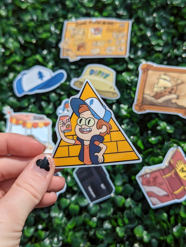 May include: A die-cut vinyl sticker featuring a cartoon character with brown hair wearing a blue and white cap, an orange shirt, and a dark vest. The character stands in front of a yellow triangle with brick patterns and holds a pink soda can.