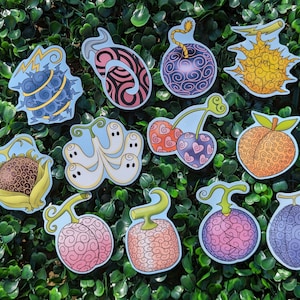 May include: A collection of eleven colorful stickers featuring stylized fruit designs with intricate swirl patterns. The stickers include various shapes such as spheres, a cherry pair, a peach, and a ghost-like cluster, all with distinct outlines.
