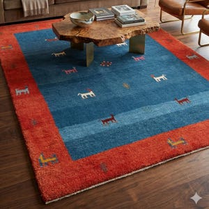 Puede incluir: Una alfombra rectangular azul con borde rojo. Presenta un patrón de pequeñas figuras de perros en varios colores. La alfombra está en un salón con un sofá marrón y una mesa de centro de madera.