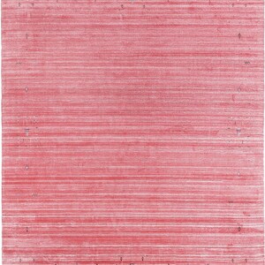 Puede incluir: Una alfombra rectangular con una base de color rojo vibrante y estr&iacute;as horizontales blancas en toda la superficie. El borde est&aacute; definido por una serie de peque&ntilde;os motivos geom&eacute;tricos espaciados en tonos apagados de azul, amarillo y marr&oacute;n oscuro.