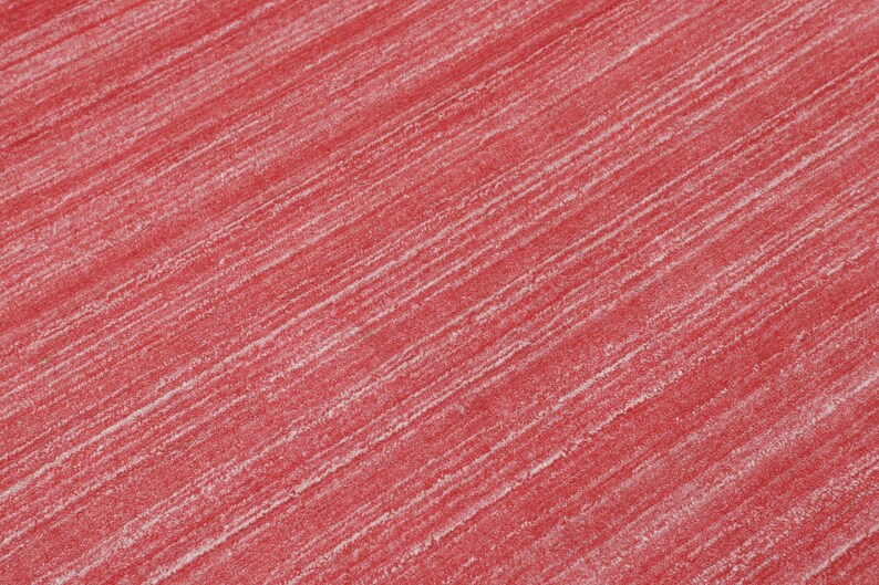Puede incluir: Una superficie de tela texturizada con un color base rojo vibrante y finas rayas blancas diagonales que atraviesan el material, creando una apariencia jaspeada sutil con un patr&oacute;n lineal consistente y repetitivo en todo el textil.