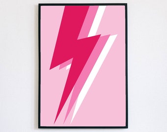 May include: A framed art print featuring a pink and white lightning bolt design on a light pink background. The artwork is encased in a black frame and hangs on a white wall above a white couch.