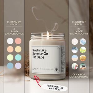 May include: A white soy candle with a clear glass jar and a label that reads "Smells Like Summer On The Cape". The sweet smell of ocean breezes and sandy toes.  The candle is on a white surface with a red arrow pointing to the text "Personalize Any Text".
