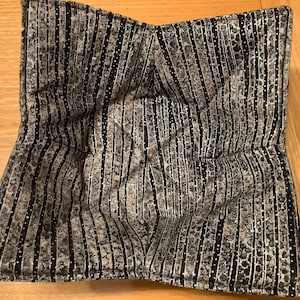 May include: A black and white striped fabric bowl liner with a subtle speckled pattern. The liner is made of a soft, quilted fabric and is designed to protect bowls from scratches and heat.