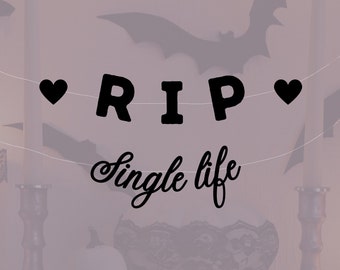 May include: A Halloween-themed banner with the text "RIP Single life" in black script, flanked by black heart shapes. Silhouettes of bats are visible in the background, creating a spooky atmosphere. The banner is strung across a soft, muted background.