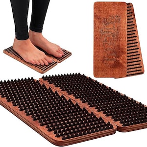 May include: Wooden foot massage boards with dark brown plastic spikes. One board is being used, while another board and a foot reflexology chart are also visible. The boards are made of light brown wood.