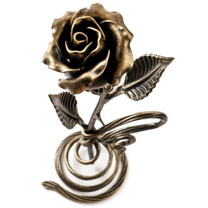 May include: A gold metal rose with a spiral base. The rose is crafted with intricate details, including leaves and a stem.
