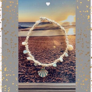 May include: A cream-colored macrame anklet with a seashell charm and light blue and white beads. The charm is a seashell with a teal and white design. The anklet is displayed against a beach scene.