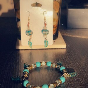 Puede incluir: Un brazalete turquesa y dorado con abalorios de hojas y un par de pendientes turquesa y dorado con detalles de hojas.