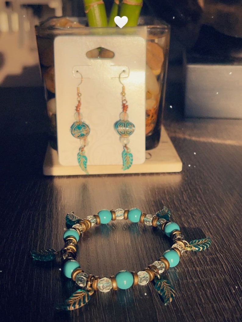 Puede incluir: Un brazalete turquesa y dorado con abalorios de hojas y un par de pendientes turquesa y dorado con detalles de hojas.