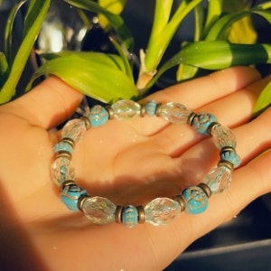Puede incluir: Un brazalete de cuentas de cristal turquesa y transparente con detalles dorados. El brazalete est&aacute; hecho de peque&ntilde;as cuentas redondas con un dise&ntilde;o floral.