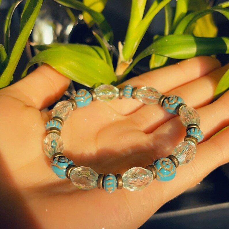 Puede incluir: Un brazalete de cuentas de cristal turquesa y transparente con detalles dorados. El brazalete est&aacute; hecho de peque&ntilde;as cuentas redondas con un dise&ntilde;o floral.