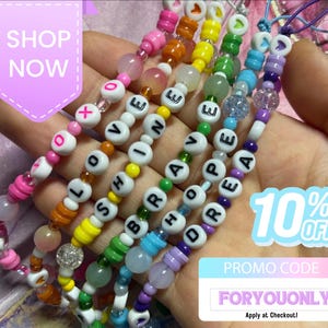 May include: Five beaded phone charms featuring colourful plastic beads and letter beads spelling out LOVE, SHINE, BRAVE, HOPE, and DREAM. The charms include pink, orange, yellow, green, blue, and purple beads with text overlays SHOP NOW, 10% OFF, and PROMO CODE FORYOUONLY.
