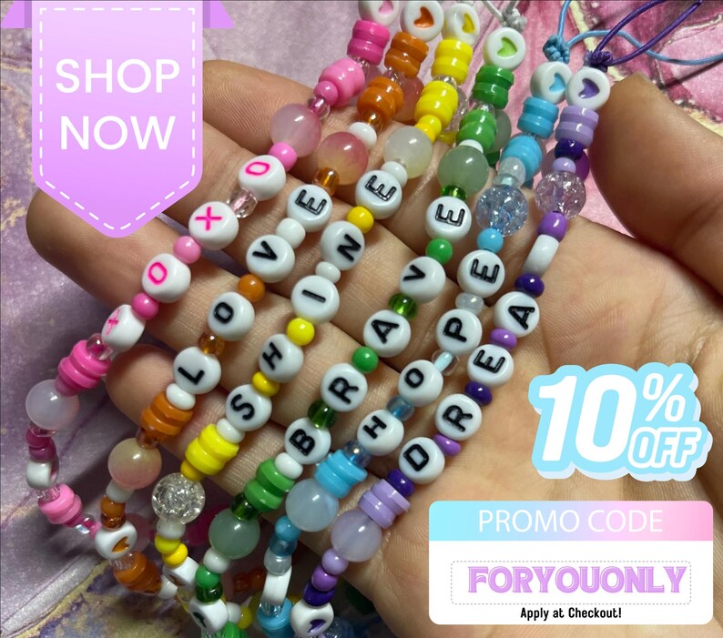May include: Five beaded phone charms featuring colourful plastic beads and letter beads spelling out LOVE, SHINE, BRAVE, HOPE, and DREAM. The charms include pink, orange, yellow, green, blue, and purple beads with text overlays SHOP NOW, 10% OFF, and PROMO CODE FORYOUONLY.
