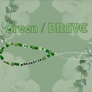 May include: A phone charm featuring green and white beads, including round green beads, small green and white seed beads, and white letter beads spelling the word BRAVE. The charm includes small green heart accents and a white loop attachment.