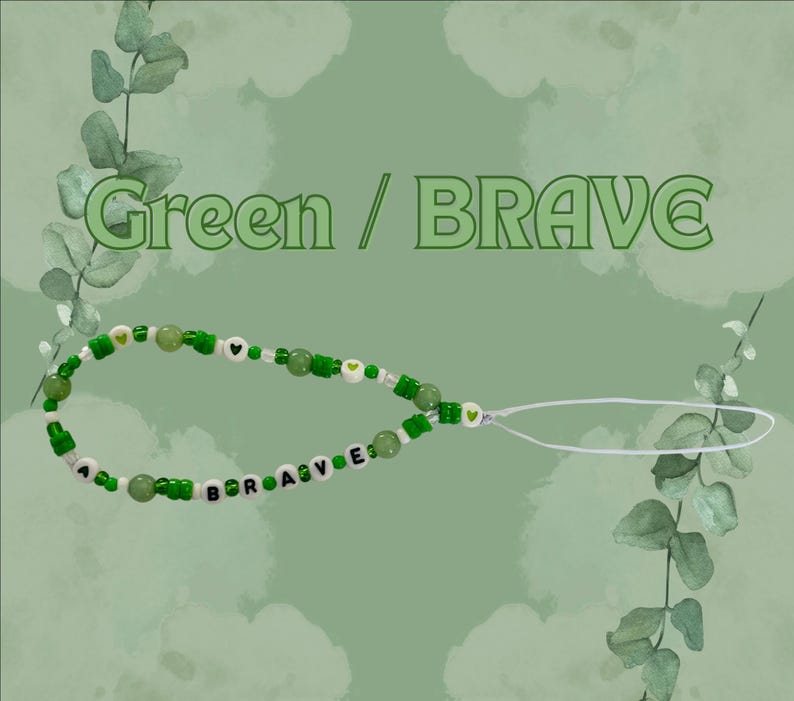 May include: A phone charm featuring green and white beads, including round green beads, small green and white seed beads, and white letter beads spelling the word BRAVE. The charm includes small green heart accents and a white loop attachment.