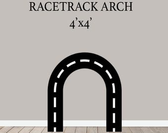 May include: Black racetrack arch with white dashed lines, against a gray wall. The text "RACETRACK ARCH" is above the arch, with "4'x4'" below it. The arch is a decorative element, possibly for a child's room or event.