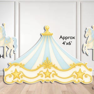 May include: A carousel-themed party decoration set featuring two cream-colored horses with blue manes and saddles, each 26 inches high, and a central tent canopy with blue and white stripes, gold star accents, and gold trim, measuring approx 4'x6'.