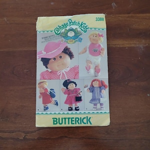 Pode incluir: Um envelope de molde de costura Butterick 3388 Cabbage Patch Kids com ilustrações de bonecas em várias roupas, incluindo um vestido rosa de bolinhas com chapéu, um conjunto de babador branco, um vestido vermelho, um rosa e um roxo com bolsa.