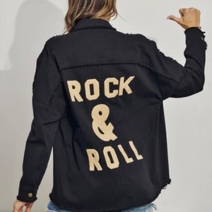 May include: Black denim jacket with a distressed hem and a gold embroidered "Rock & Roll" design on the back.