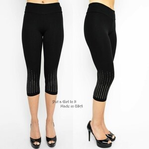 May include: Black cropped leggings with a row of silver rhinestones down the sides. The leggings are made in the USA. "Put a Girl in It" is written below the leggings.