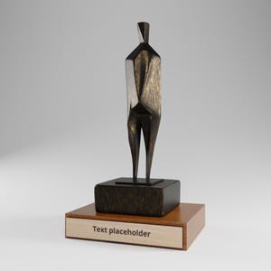 May include: A bronze-toned abstract human figure sculpture with a faceted, geometric design. The figure stands on a dark, textured rectangular base, which is mounted on a larger wooden plinth featuring a light-colored plaque with the text Text placeholder.