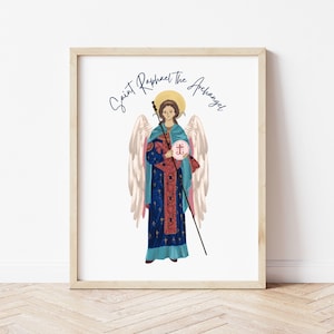 May include: Framed print featuring an illustration of Saint Raphael the Archangel. The artwork depicts a figure with wings, wearing blue and red robes, holding a staff and a circular emblem. The text "Saint Raphael the Archangel" is written above the figure.