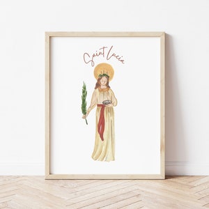 May include: A printable art print featuring a watercolor illustration of Saint Lucia, a Christian saint. The illustration depicts Saint Lucia holding a bowl and a palm branch. The text "Saint Lucia" is written in cursive at the top of the print.