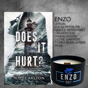 May include: A black candle with a wooden lid and a white shark logo. The candle is labeled "ENZO DOES IT HURT?" and the text "LEMON, EUCALYPTUS, FIR NEEDLE, PEPPERMINT, CEDARWOOD, SANDALWOOD, CLOVE, OAKMOSS, TONKA BEAN, AMBER, MUSK" is printed on the side. The candle is next to a book cover with the title "DOES IT HURT?" and the author "H.D. CARLTON".