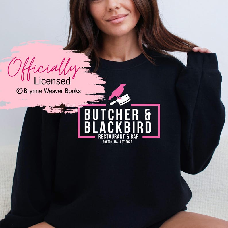 May include: Black sweatshirt with a pink graphic design that says "Butcher & Blackbird Restaurant & Bar Boston, MA Est. 2023" with a black crow holding a butcher knife.