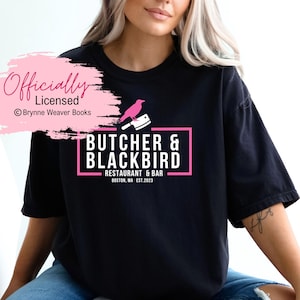 以下が含まれることがあります： 「Butcher & Blackbird Restaurant & Bar Boston, MA Est. 2023」とピンク色のロゴが書かれた黒いTシャツ。ロゴには、ピンク色のナイフの上にピンク色の鳥がとまっているデザインも含まれています。