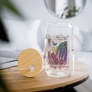 May include: A glass water bottle with a bamboo lid and straw. The bottle features a floral design and the text "You are worth more than many sparrows Luke 12:6".