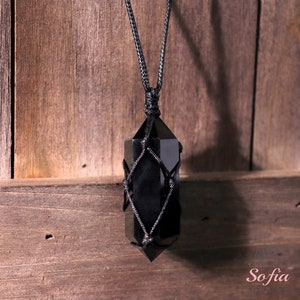May include: Black obsidian crystal point pendant necklace with a black cord and a macrame knot design.