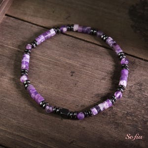 May include: A purple and silver beaded bracelet with a magnetic clasp. The beads are made of amethyst and hematite.