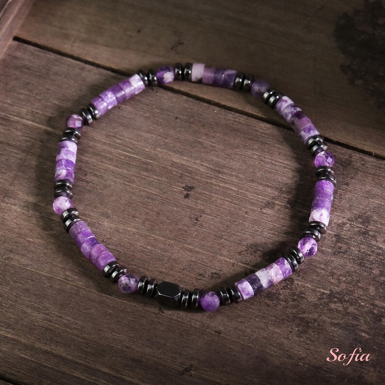 May include: A purple and silver beaded bracelet with a magnetic clasp. The beads are made of amethyst and hematite.