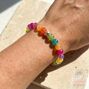 May include: A stretch bracelet composed of small, smooth, translucent spherical beads in a spectrum of colors including red, orange, yellow, green, blue, and purple, accented by a single polished silver-toned metal bead centered in the design.