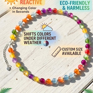 May include: A beaded necklace featuring round, translucent beads in various colors including red, orange, yellow, green, blue, and purple. The necklace includes a silver-toned metal chain extender with a small heart-shaped charm at the end.