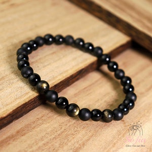 Peut inclure: Bracelet en perles noires avec des accents dor&eacute;s. Le bracelet est compos&eacute; de perles d'onyx noir et de pyrite dor&eacute;e.