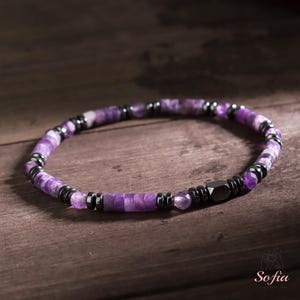 May include: A purple amethyst and black hematite beaded bracelet. The bracelet is made with small, faceted amethyst beads and black hematite beads.