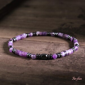 May include: A purple and black beaded bracelet with a magnetic clasp. The bracelet is made with amethyst and hematite beads.