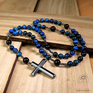 Pu&ograve; includere: Un rosario di perline blu e nere con una croce in ematite. Le perline sono fatte di occhio di tigre blu e onice nero.