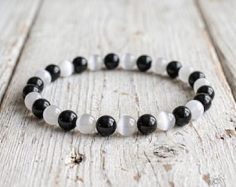 May include: A stretch bracelet composed of alternating smooth, spherical beads in solid black and translucent white. The beads are arranged in a repeating pattern, creating a circular band. A small logo with the text Sofia is visible in the corner.
