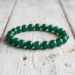 May include: A circular bracelet composed of smooth, polished, deep green spherical beads. The beads are uniform in size and strung together in a continuous loop, showcasing a consistent dark emerald hue and a reflective, glossy surface finish.