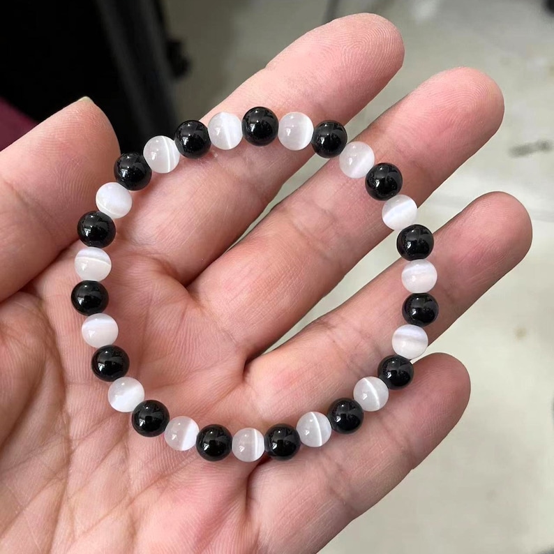 Peut inclure: Un bracelet en perles noires et blanches avec des perles rondes altern&eacute;es noires et blanches. Le bracelet est fait de pierres naturelles.