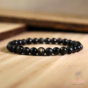 Peut inclure: Bracelet en perles noires avec des reflets dor&eacute;s. Le bracelet est compos&eacute; de perles noires mates et de perles de pyrite dor&eacute;e.